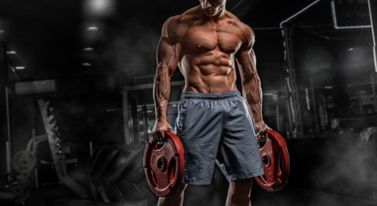 Male athlete bodybuilder posing on a black background