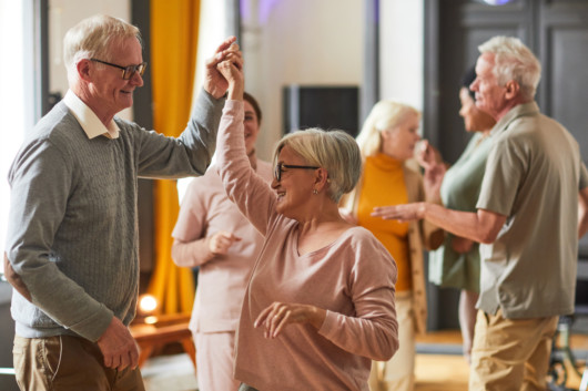 Group of smiling senior people dancing while enjoying activities in retirement home